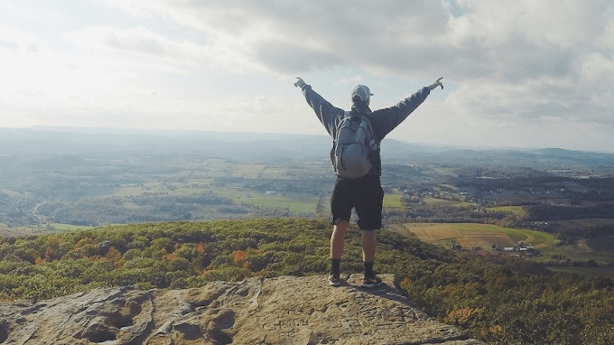 Hiker Standing On Top Of Mountain